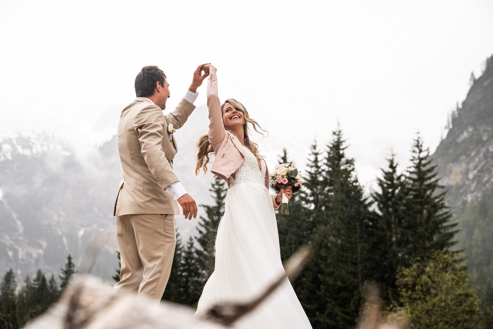 Lo sposo fa girare la sposa, dietro abeti e montagne nella nebbia