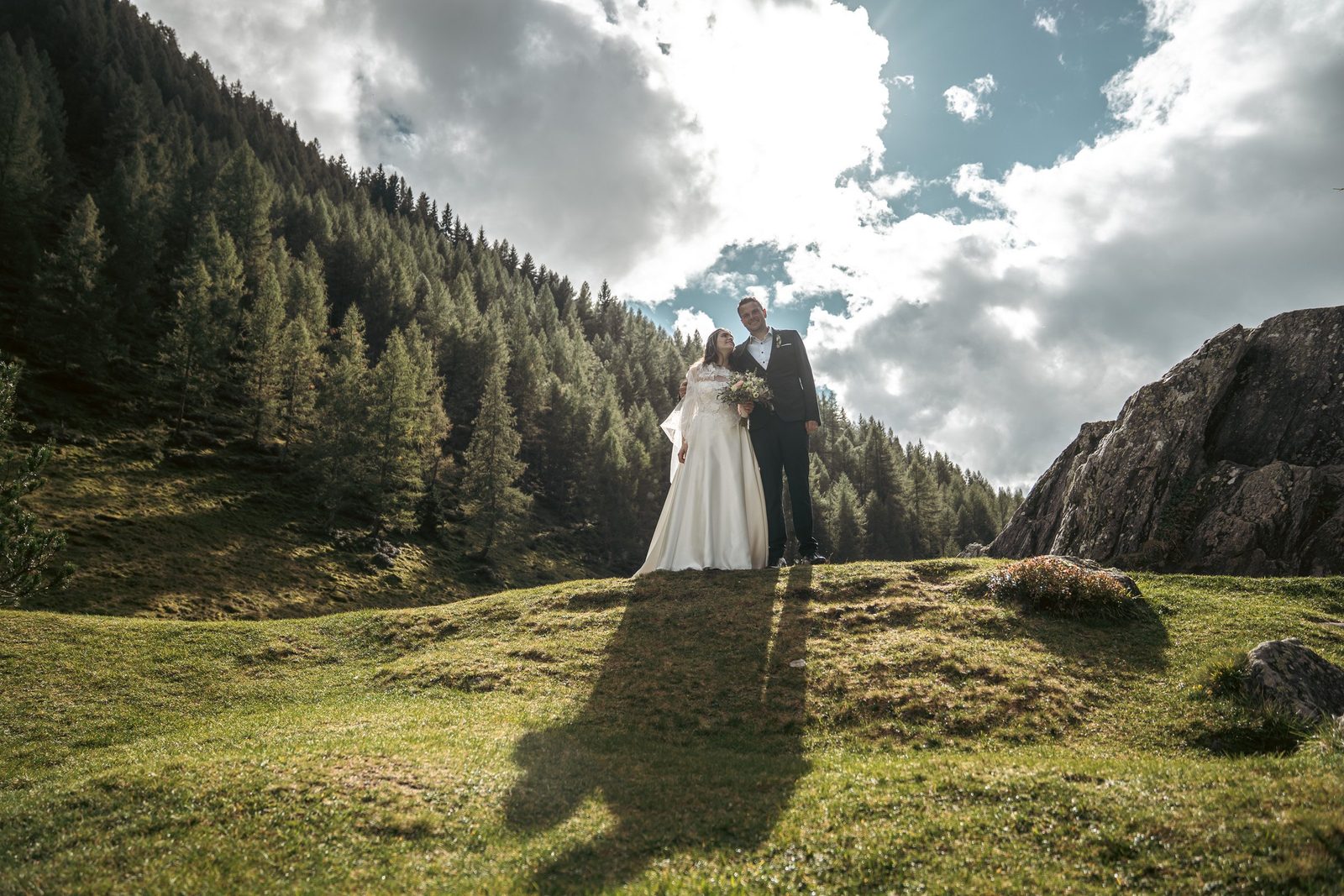 La coppia piccola in un ampio prato di montagna sotto le nuvole