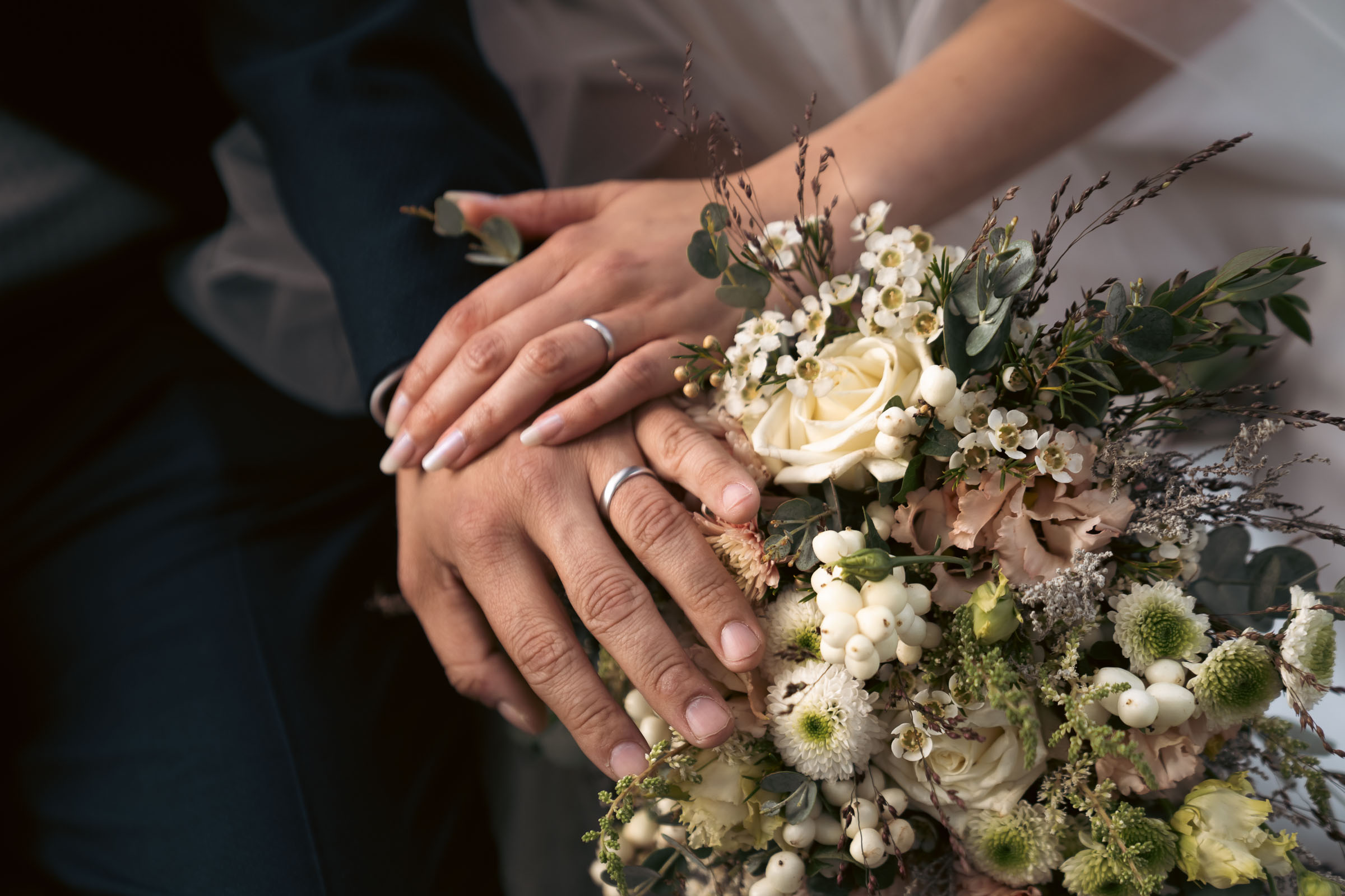 Hands resting on a bouquet of roses and eucalyptus