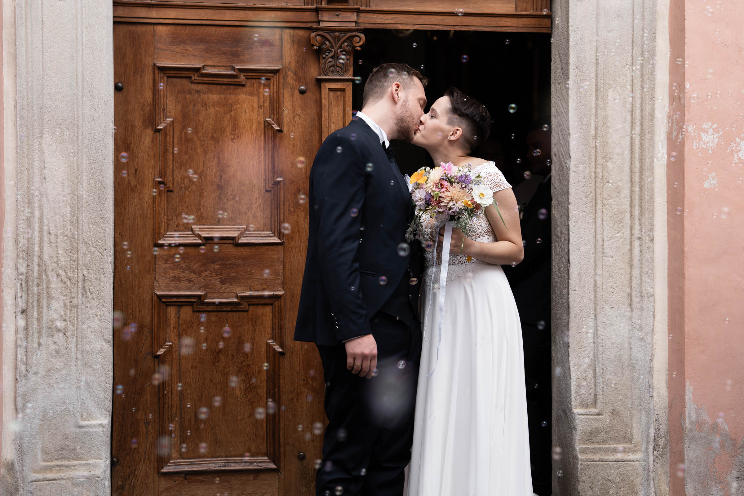 Couple kissing in a church doorway, soap bubbles in the air