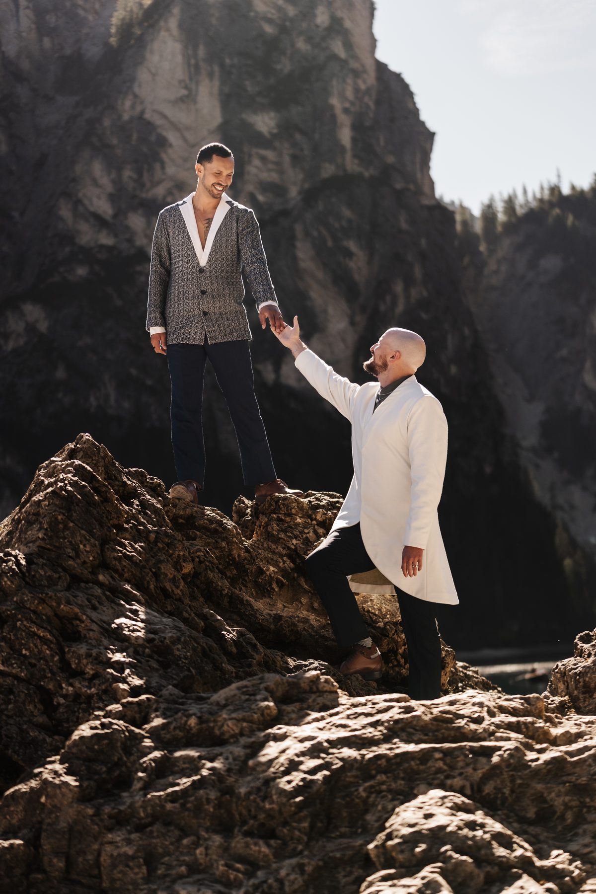 One helps the other up onto a rock by the lake