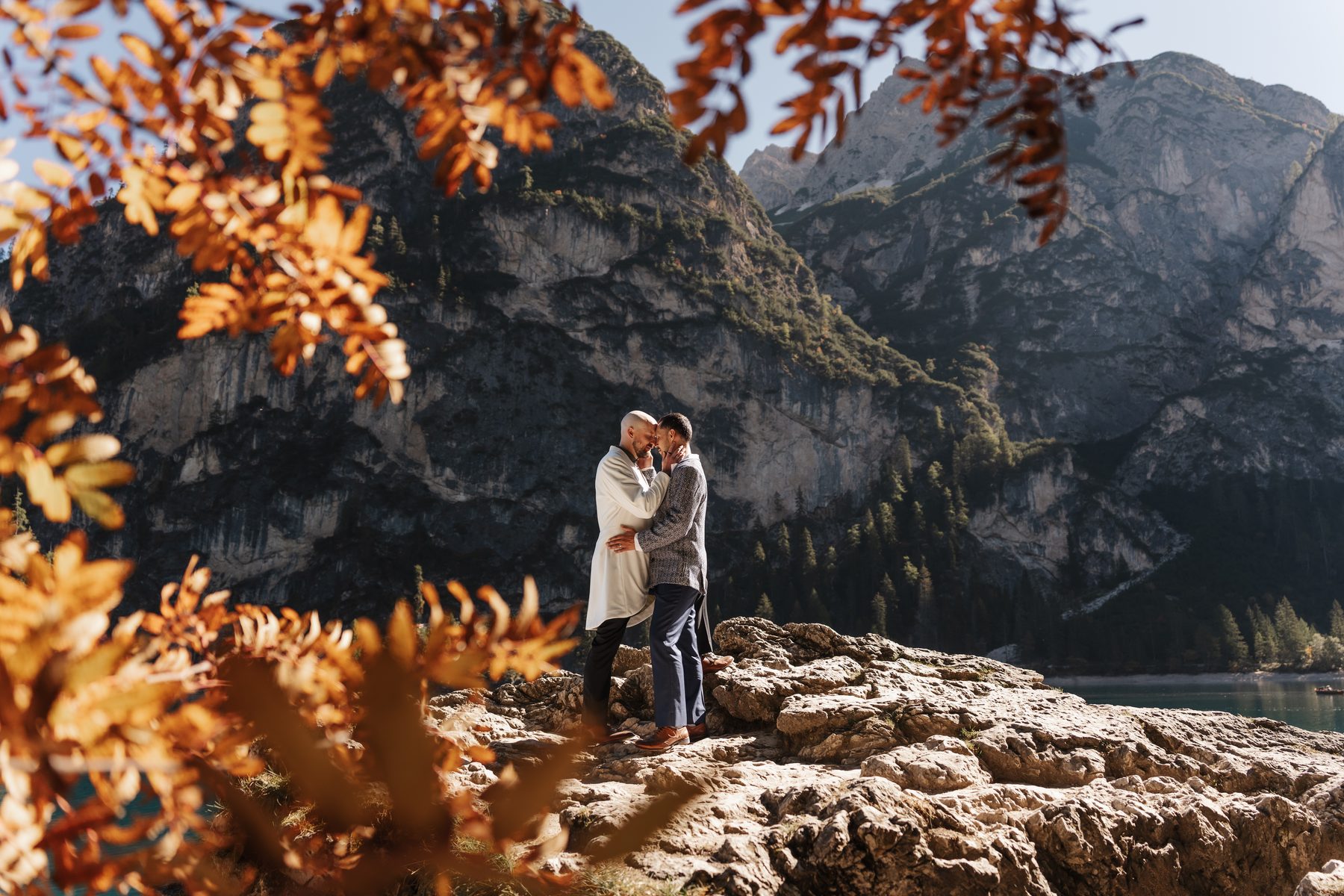 The couple on the rocks by the shore, autumn leaves in front